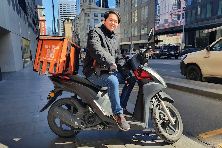 A man on a motorbike parked at a sidewalk at Melbourne CBD