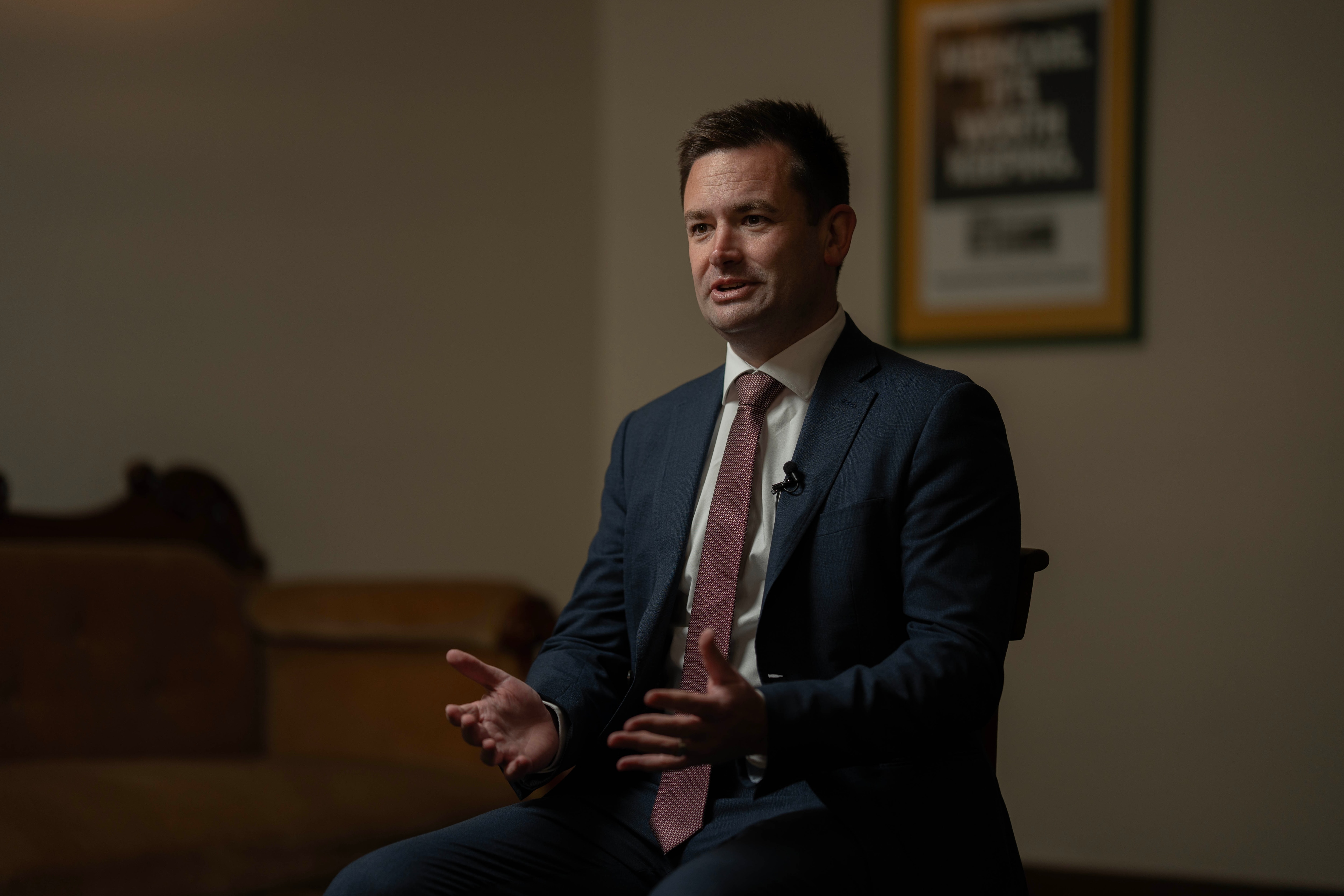A guy in a suit and tie sits in a room during an interview.