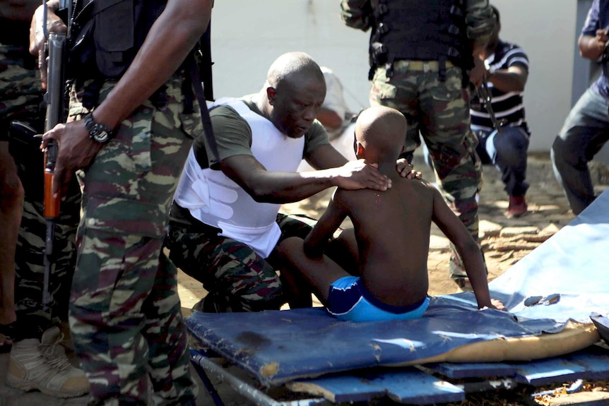 A soldier comforts an injured boy in Bassam, Ivory Coast