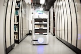 An Automated Guided Vehicle is travelling down a large stack of books.