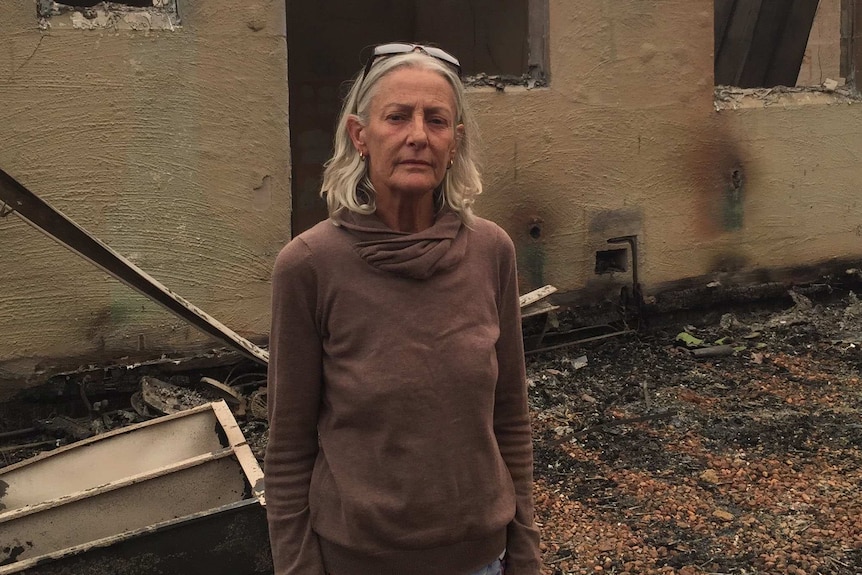 Jann Gilbert stands outside her fire damaged home in Mallacoota.