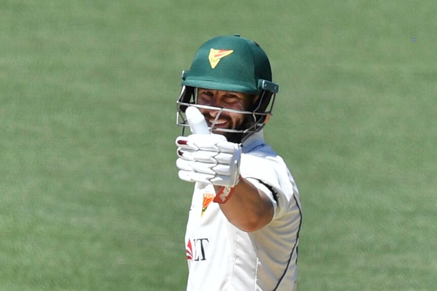 Matthew Wade holds his gloved thumb up with a smile on his face