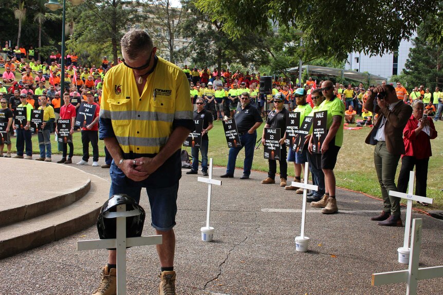 A worker lays a hard hat in memory of an Australian who died at work this year.