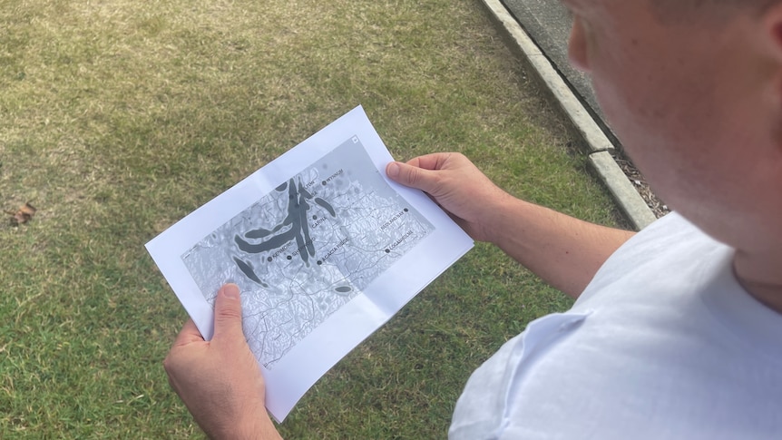 Professor Marcus Foth wears a white shirt while looking down at a piece of paper detailing the flight paths