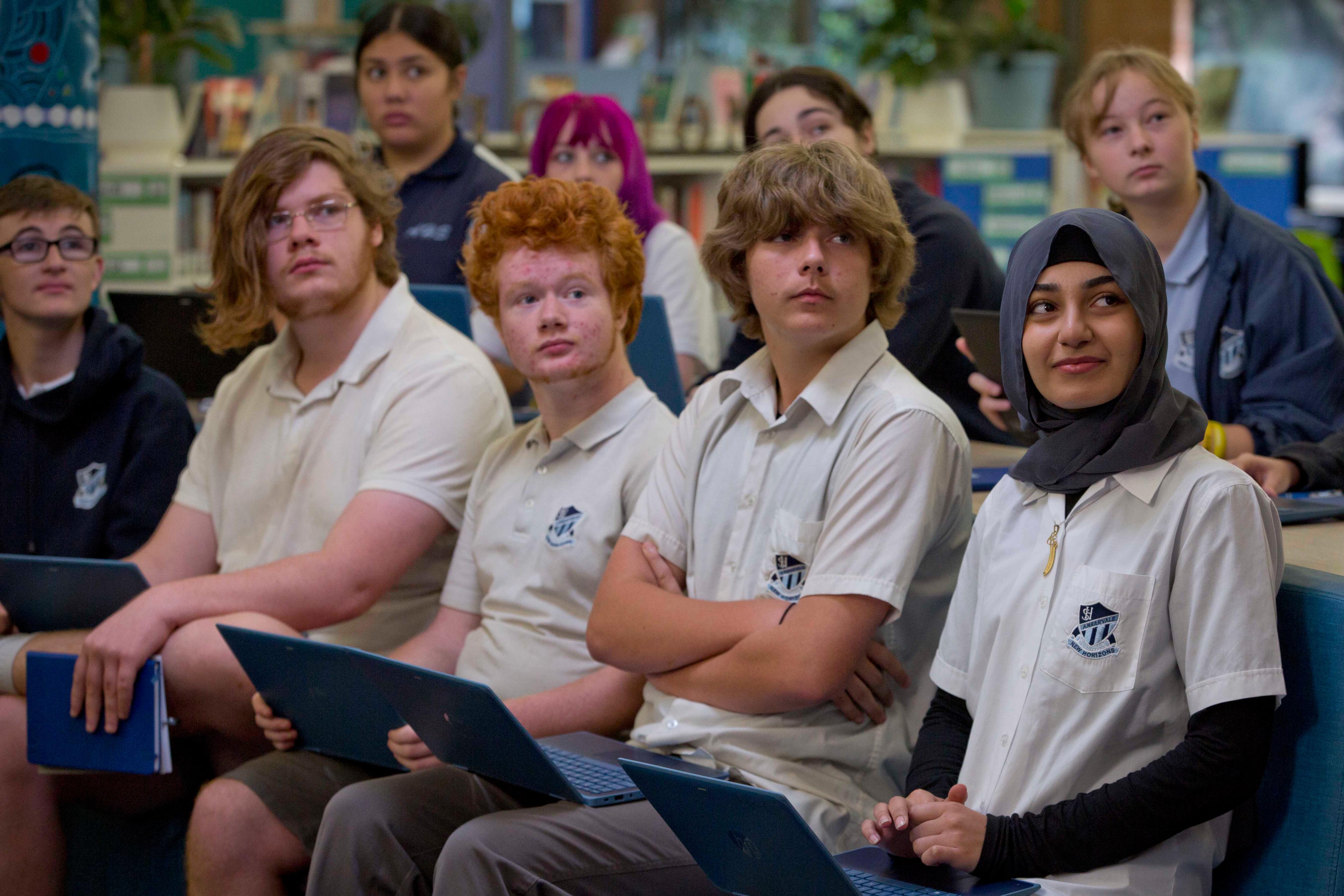 Students sit in rows in a library listening to a forum with the ABC. 