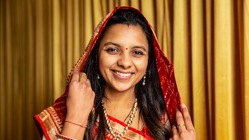 Jain Nimita Bagadia smiling and wearing red and gold sari.