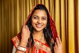 Jain Nimita Bagadia smiling and wearing red and gold sari.