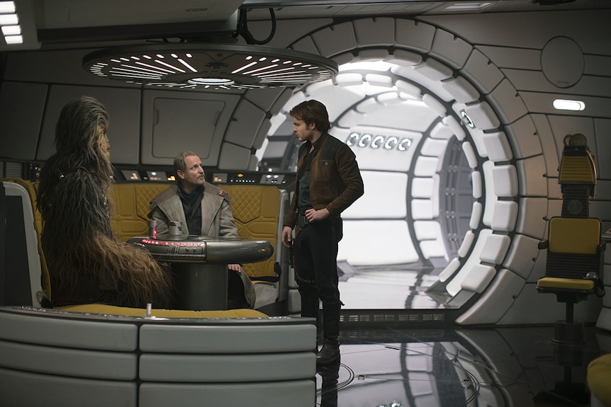 Alden Ehrenreich, Joonas Suotamo and Woody Harrelson stand in the cavern of a Star Wars space shift