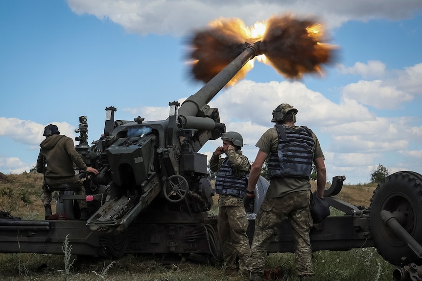 Servicemen fire a shell from a howitzer long range weapon launcher.