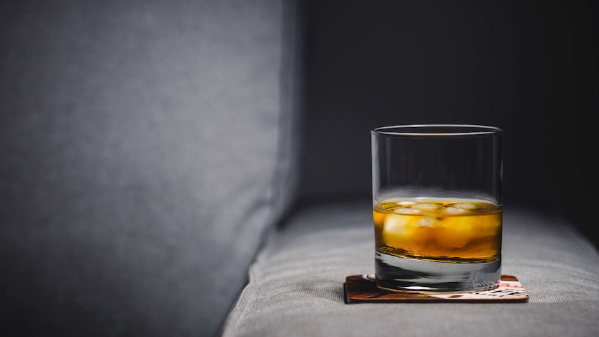 A glass with whisky sits on a coaster.