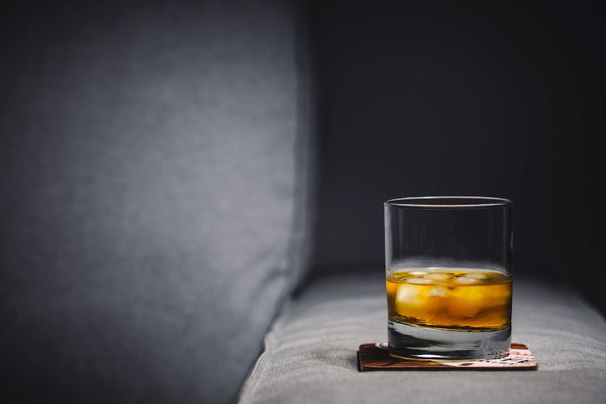 A glass with whisky sits on a coaster.