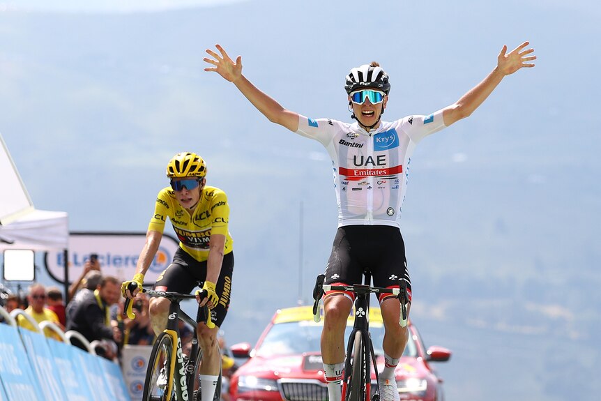 Tadej Pogacar rides with his hands up ahead of Jonas Vingegaard