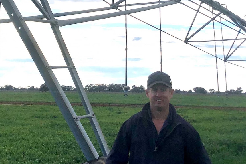 Man standing in front of irrigation equipment in green field