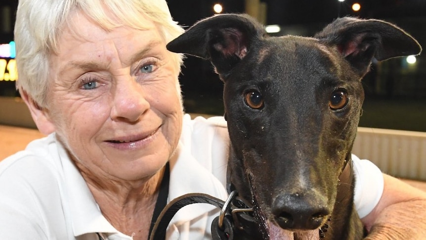 Karen Leek, a smiling middle-aged woman next to a greyhound.