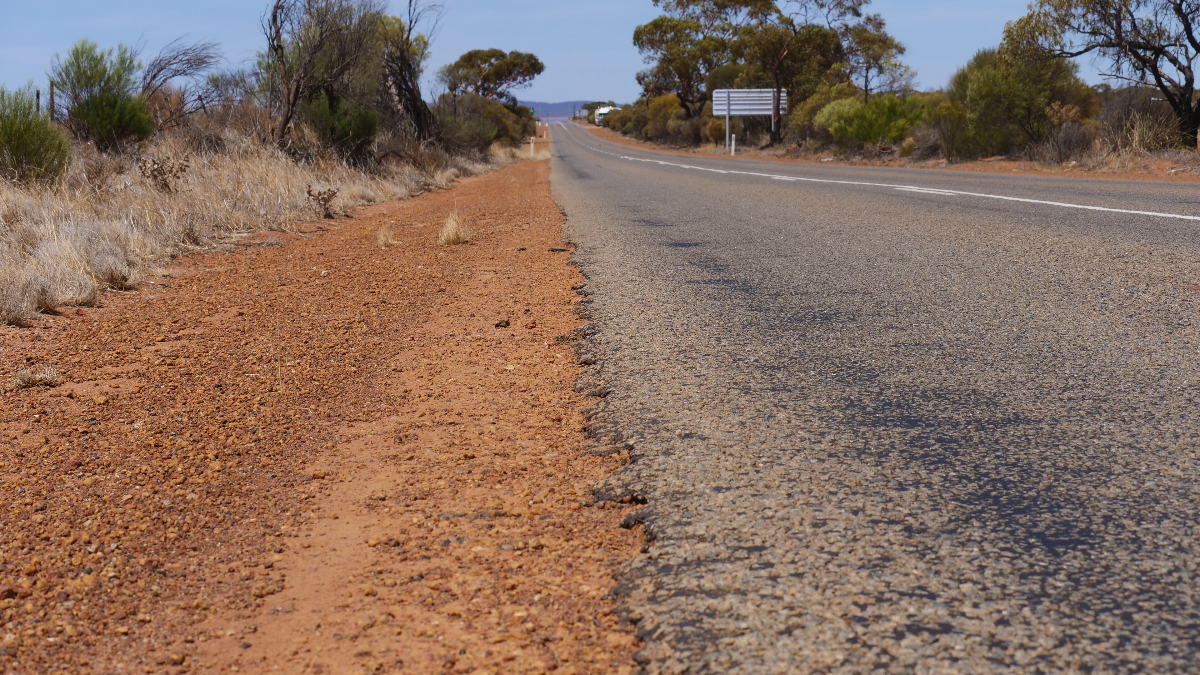 Gravel meets a stretch of road which has damaged edges. 