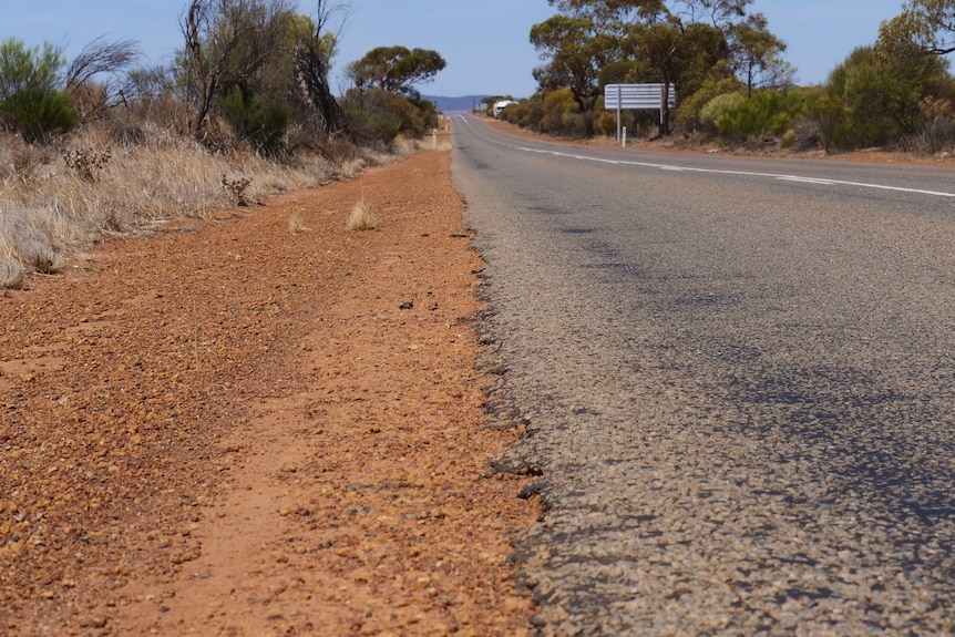 Gravel meets a stretch of road which has damaged edges. 
