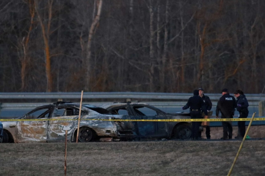 Police officers stand near badly damaged cars