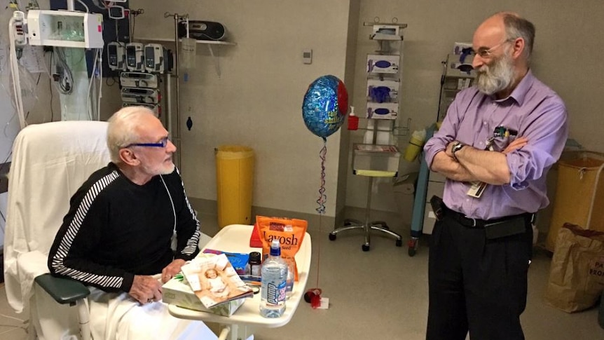 Aldrin sits as Dr Bowie stands with his arms crossed in a Christchurch hospital room