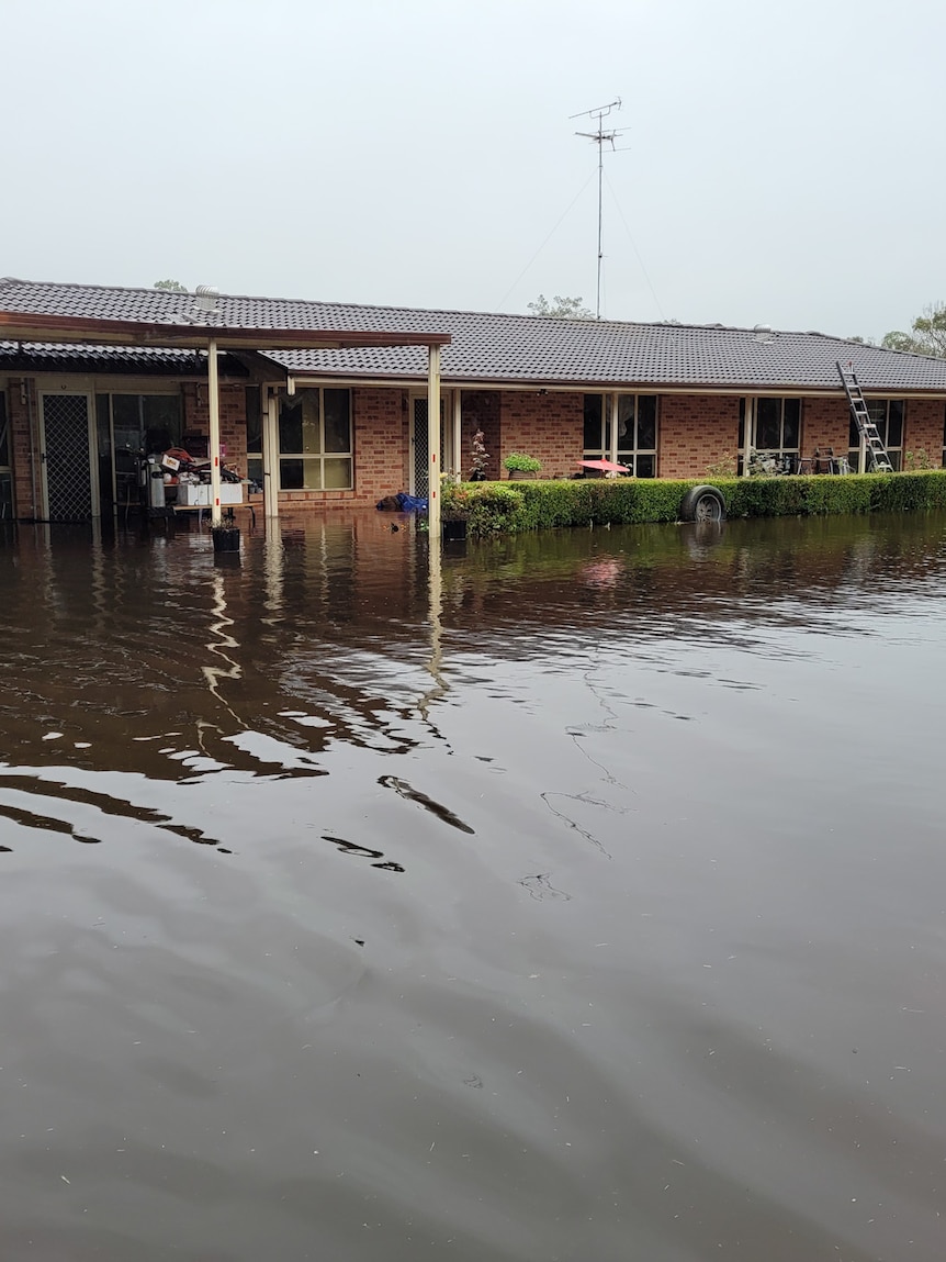 Floodwaters surround a single-storey brick house.