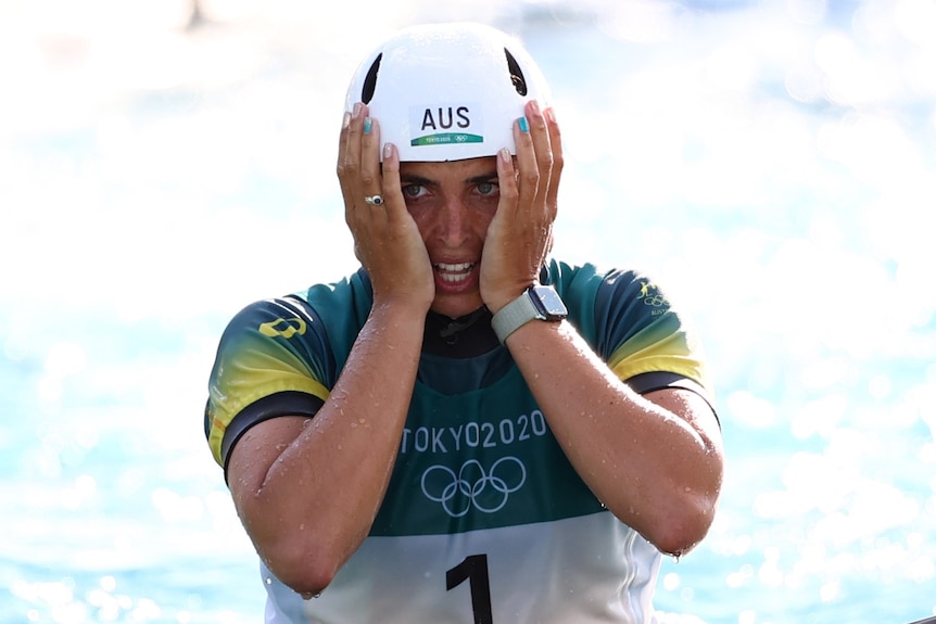 An Australian female kayaker holds her face between her two hands after placing third at the Tokyo Olympics.