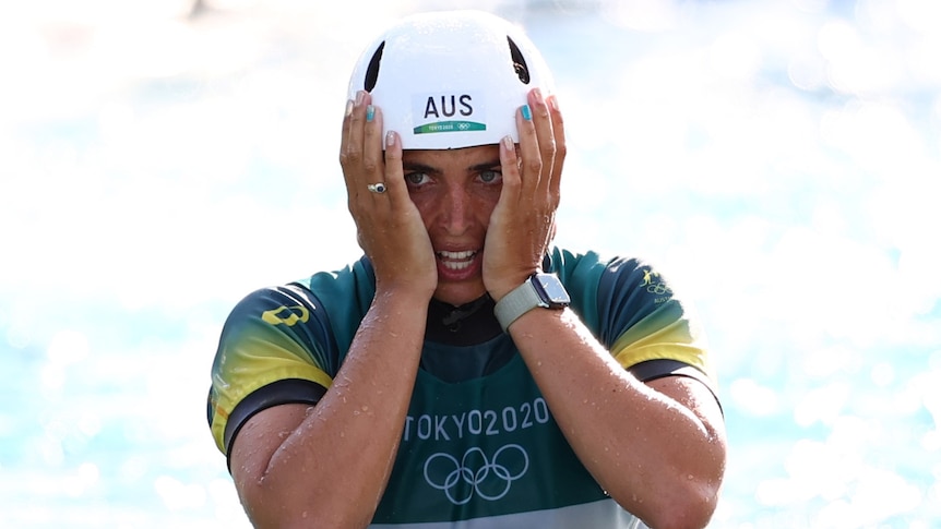 An Australian female kayaker holds her face between her two hands after placing third at the Tokyo Olympics.