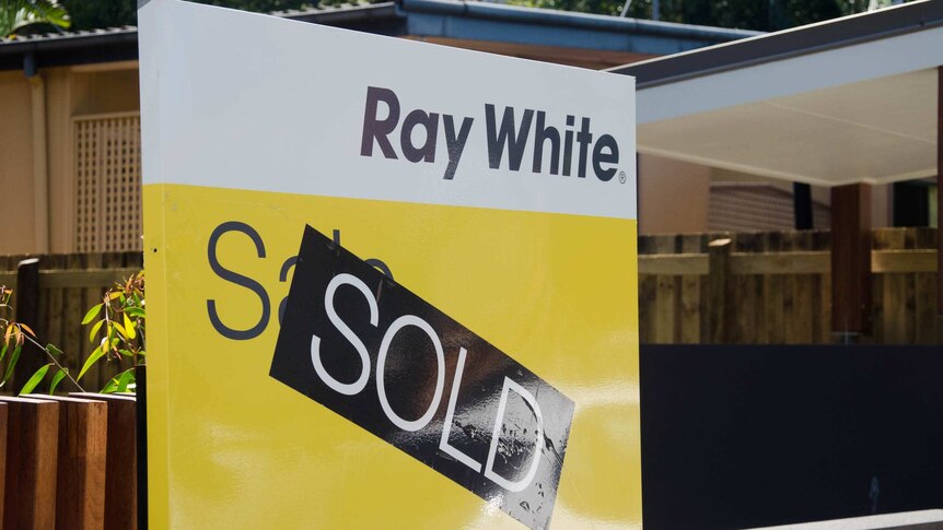 A Ray White 'Sold' sign stands outside a house
