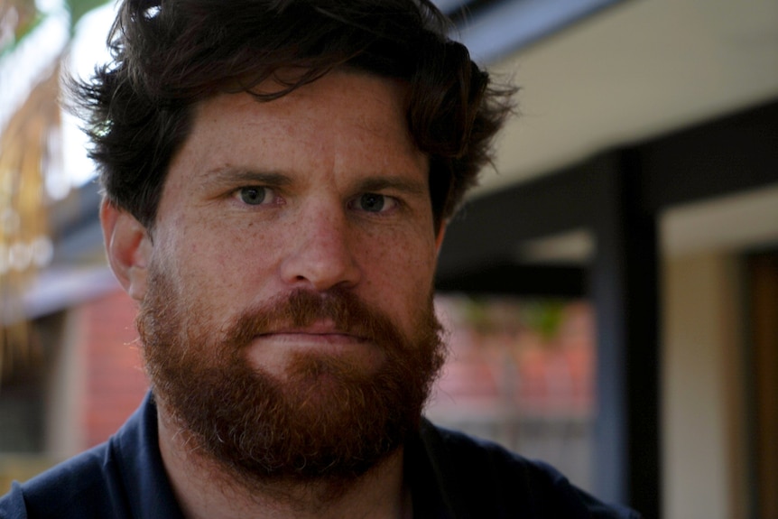 A close up of a middle aged man posing for a photo in a house.