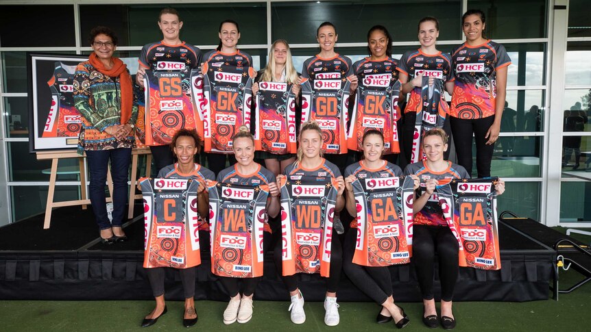 Giants Netball players hold their Indigenous playing kits in front of them.