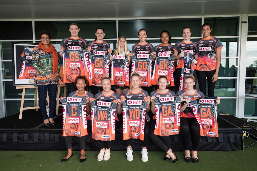 Giants Netball players hold their Indigenous playing kits in front of them.