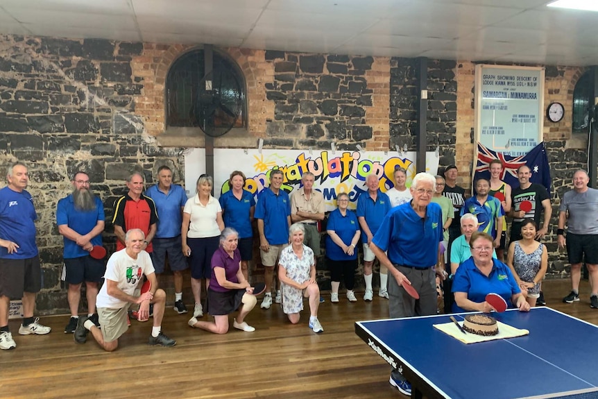 More than 20 stand behind a couple after they have been presented with a cake in recognition of the their Australia Day honours.