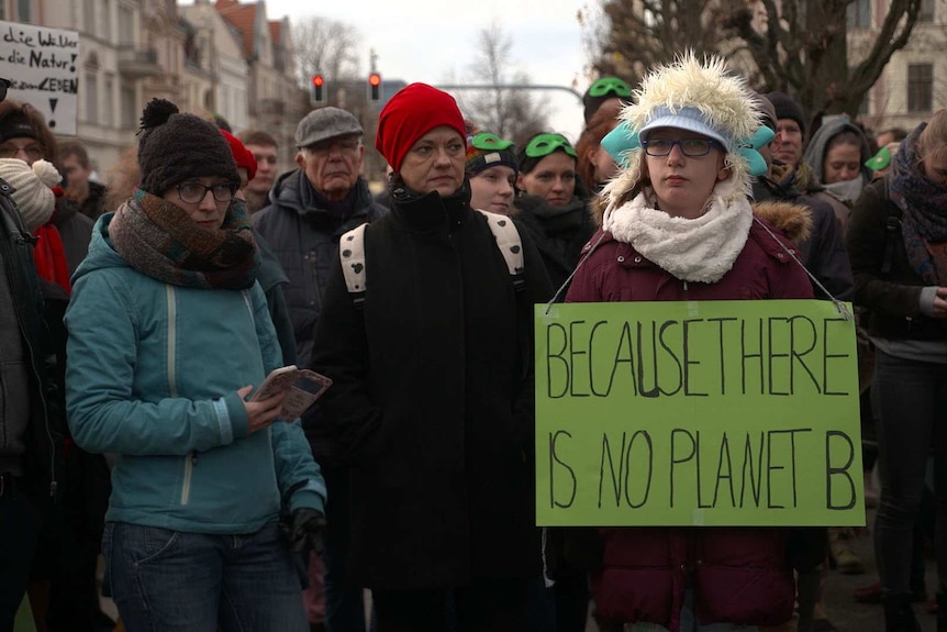 A protester with a sign around her neck reading 'because there is no planet B'.