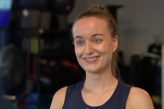 A smiling Erin Heapes stands in an F45 gym.