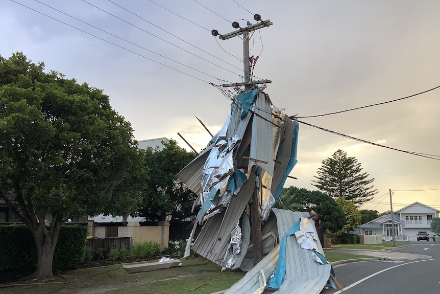 A broken metal roof caught on a power pole