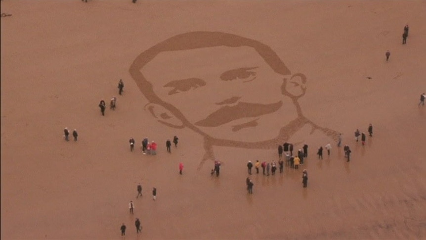 A large portrait of WWI soldier in Wilfred Owen raked into the sand.