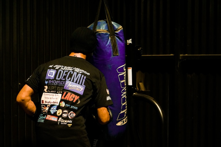 Man with blue boxing bag punching 