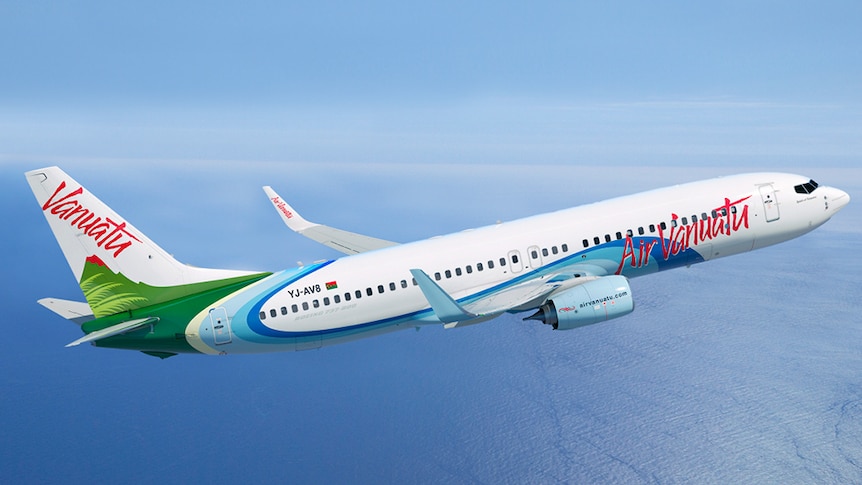 A white, green and blue Air Vanuatu plane in the sky above the blue Pacific ocean