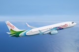 A white, green and blue Air Vanuatu plane in the sky above the blue Pacific ocean