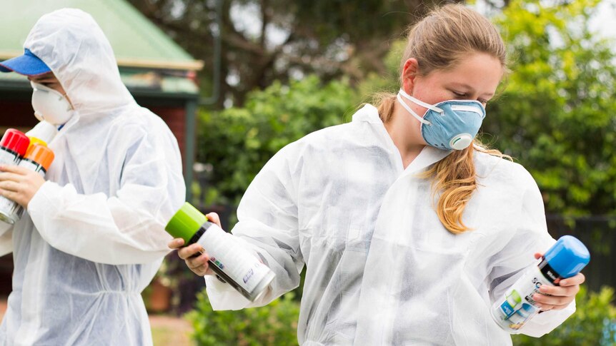 Young people holding spray paint cans.