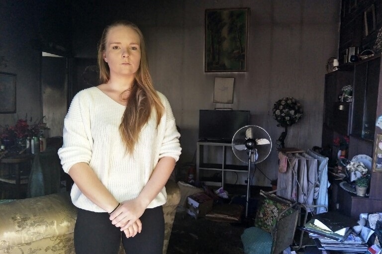 Sacha Freeman stands in neighbour's fire-damaged Redcliffe unit.