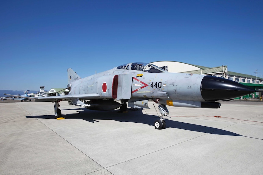A Japanese F-4 fighter jet sits on the runway.