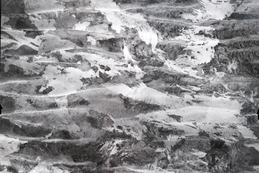 A black and white aerial image of sand dunes and fire scars.