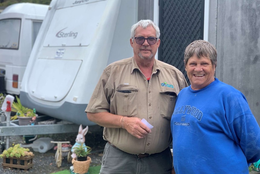 A man and woman stand in front of caravans.