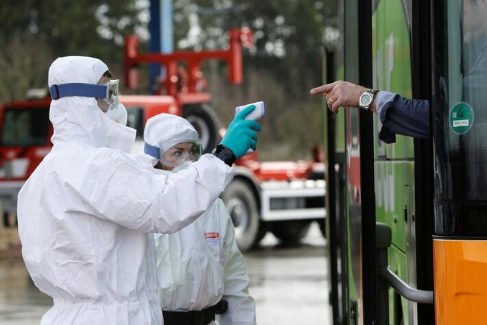Police officers in protective suits check the temperatures of a person inside a bus at Czech-German border in Rozvadov crossing,