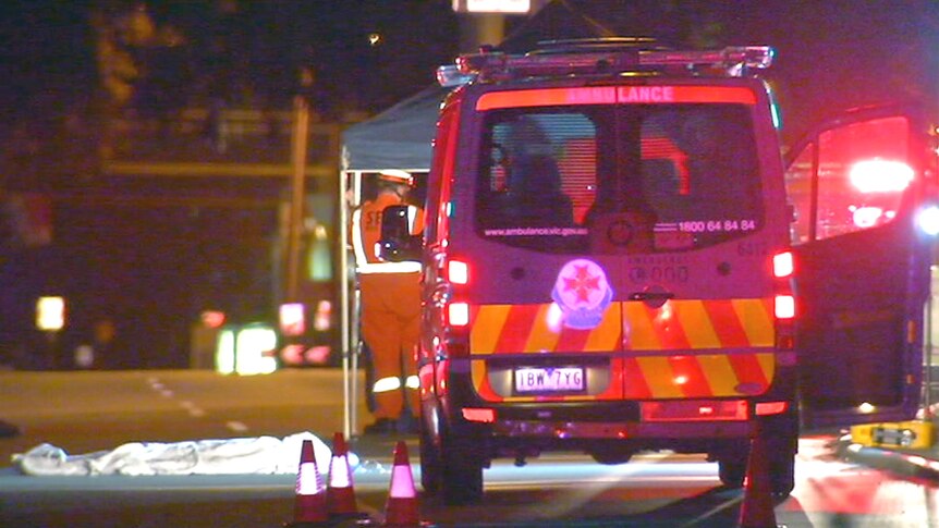 A video still of an ambulance next to a body bag, at night.