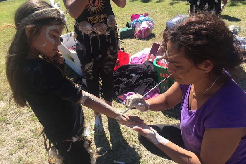 A young dancer has her armed painted.