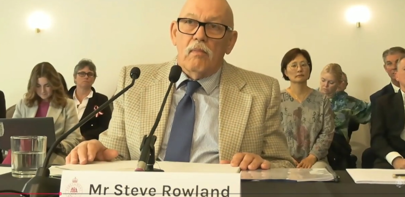 Man sitting in a chair in front of microphone.