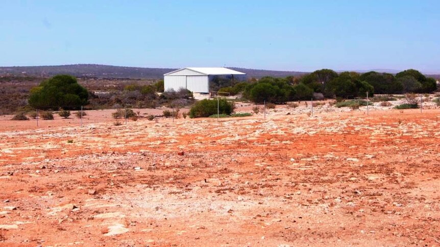 A barren red landscape with a shed in the background