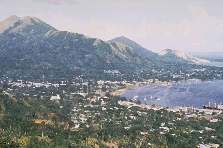 The prosperous town of Rabaul overlooked by Tavurvur (mountain furthest right) years before the eruption. (Supplied: Global Volcanism Project)