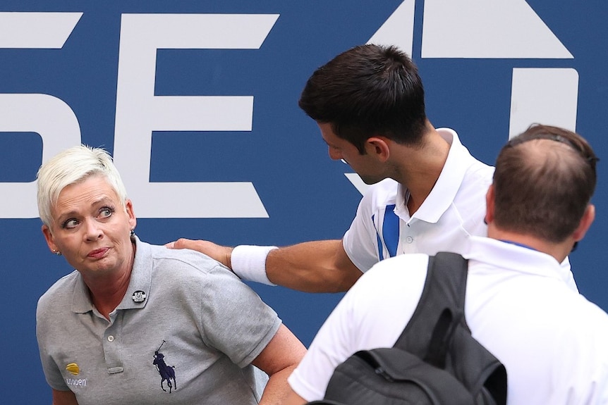 A line judge stares up at a tennis player whose hand is on her shoulder after she was hit by a ball.