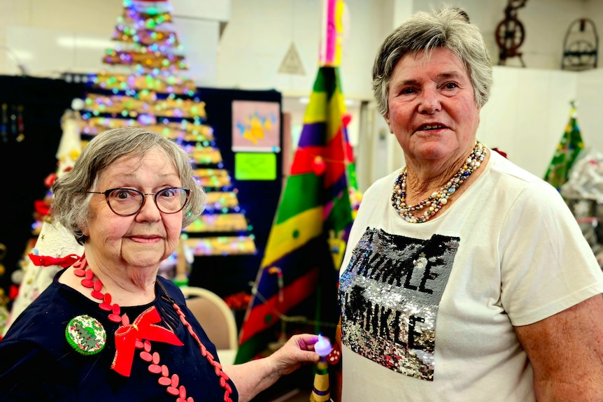 Two older women standing in front of a christmas tree